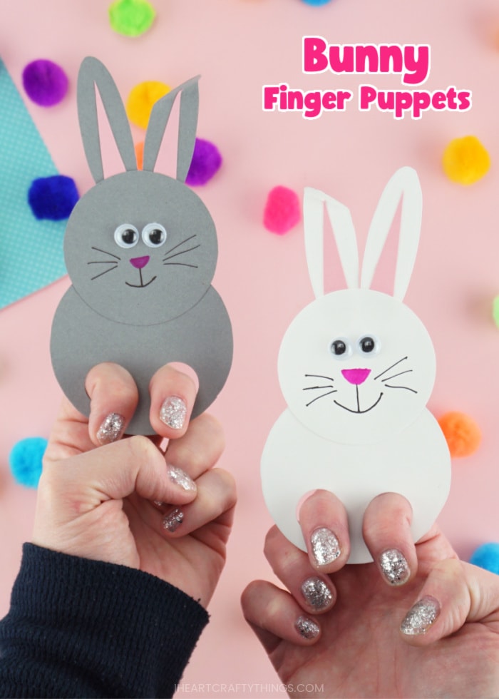 Vertical close up image of an adult showcased two finished bunny puppets, one white and one gray, with the text "bunny finger puppets" in the top right corner.